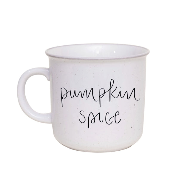 A beige ceramic coffee mug with 'PUMPKIN SPICE' hand-lettered in black on the side.
