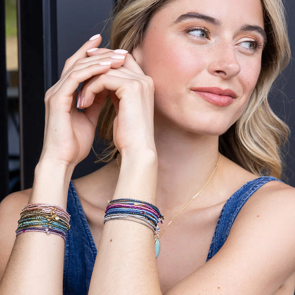 A person showcasing a trio of colorful Miyuki bracelets on their wrist.