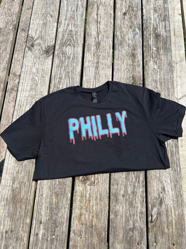 Black crop top with 'PHILLY' printed on it, placed on a wooden surface.