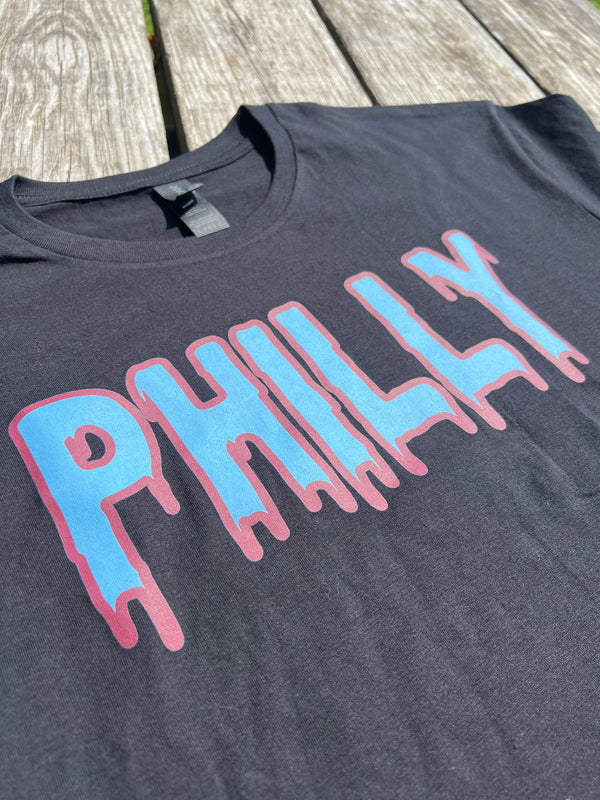 Black t-shirt with 'PHILLY' printed in blue and pink on a wooden surface