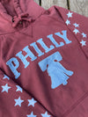 Maroon hoodie with 'PHILLY' and liberty bell graphic on a wooden surface