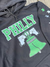 Gray hoodie with green 'PHILLY' text and Liberty Bell graphic on a wooden surface