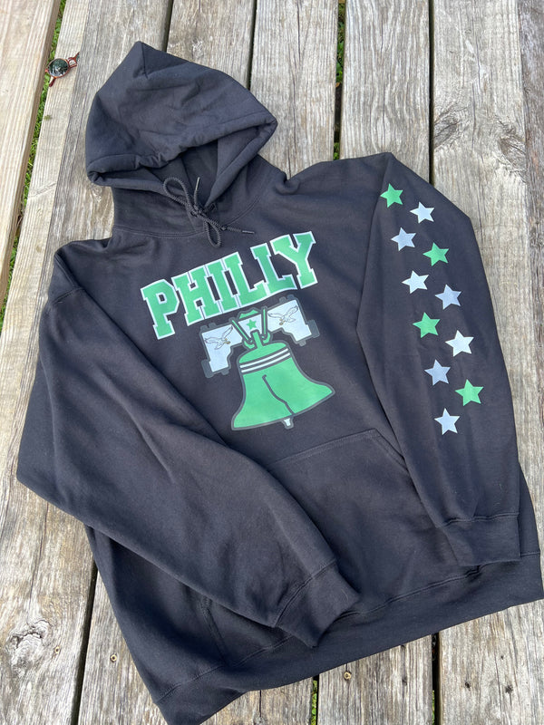 Black hoodie with 'PHILLY' and Liberty Bell graphic on a wooden surface