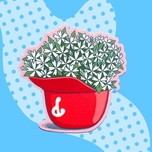 Red pot with green plants on a blue background with white polka dots