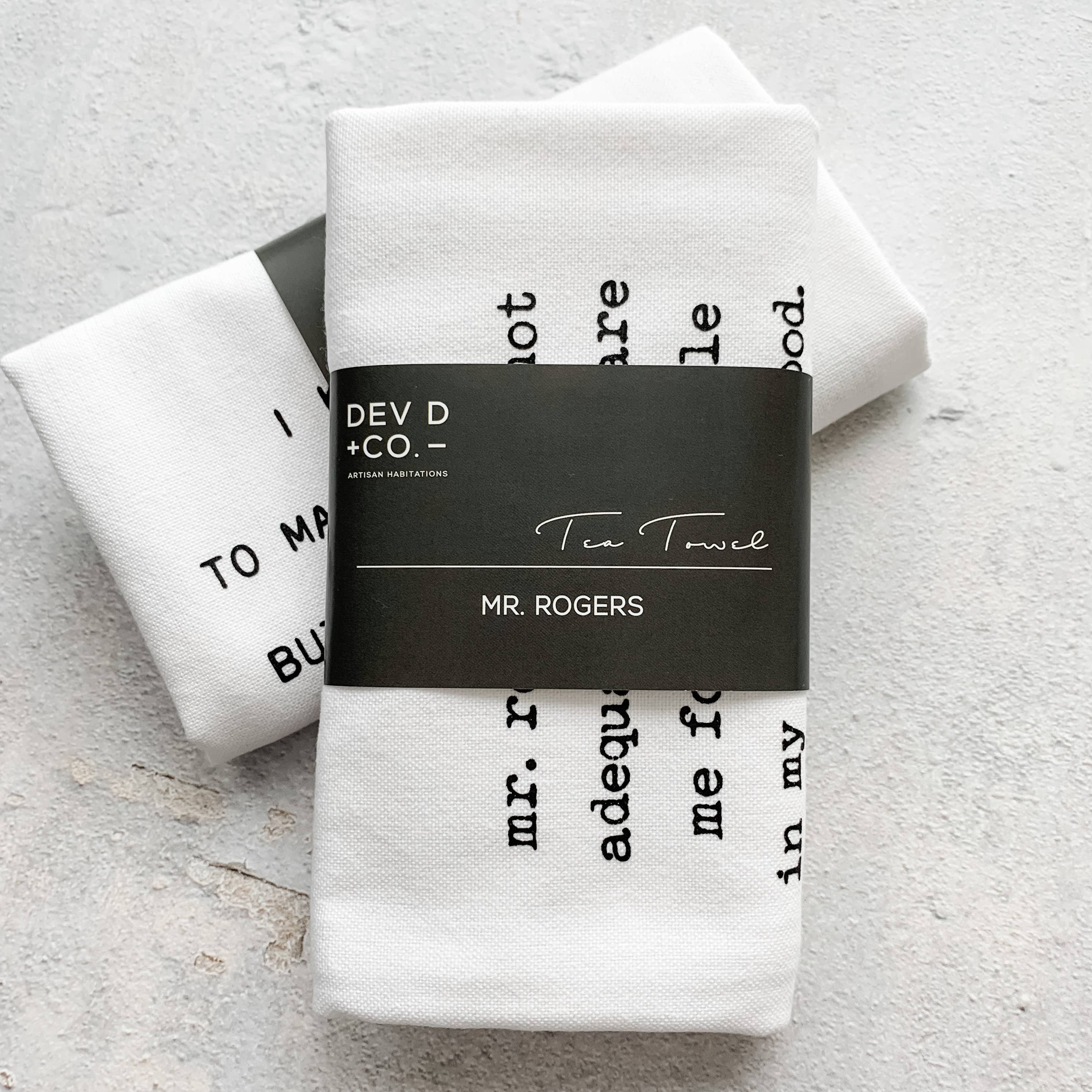 White tea towel with black text and 'DEV D + CO.' label on a light gray background