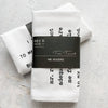 White tea towel with black text and 'DEV D + CO.' label on a light gray background