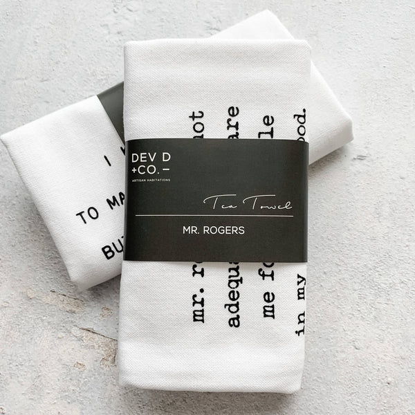 White tea towel with black text and 'DEV D + CO.' label on a light gray background
