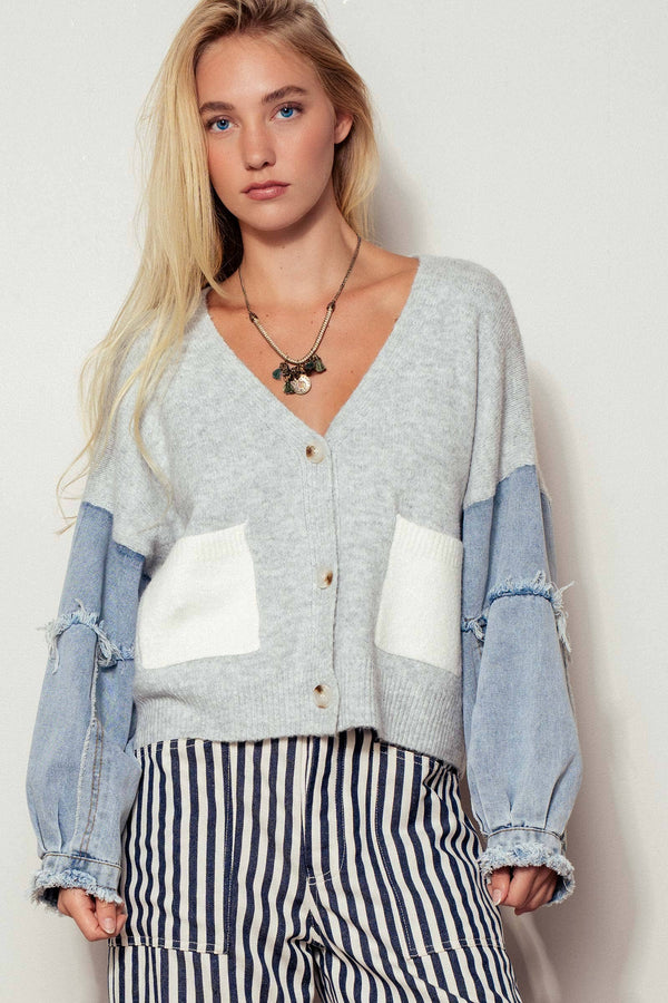 Woman wearing a patchwork cardigan with denim sleeves and striped pants against a white background