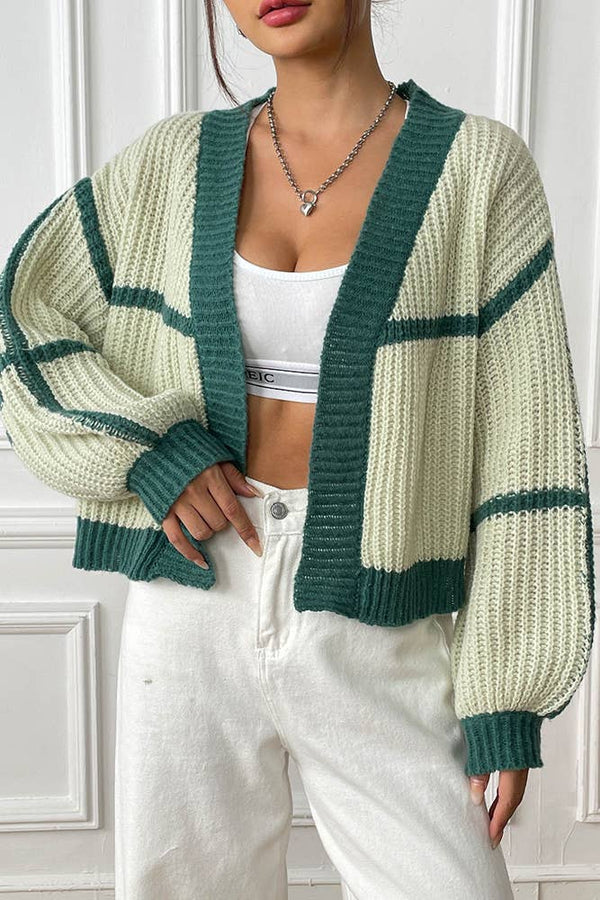 Person wearing a green and white striped cardigan with a white background