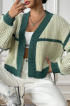 Person wearing a green and white knitted cardigan with white pants and sneakers.