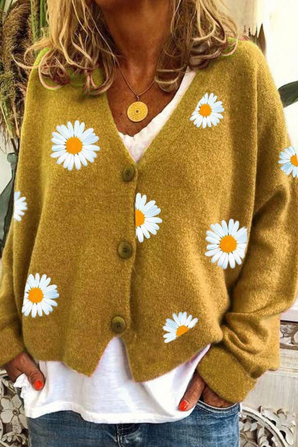 Person wearing a mustard yellow cardigan with white daisy patterns