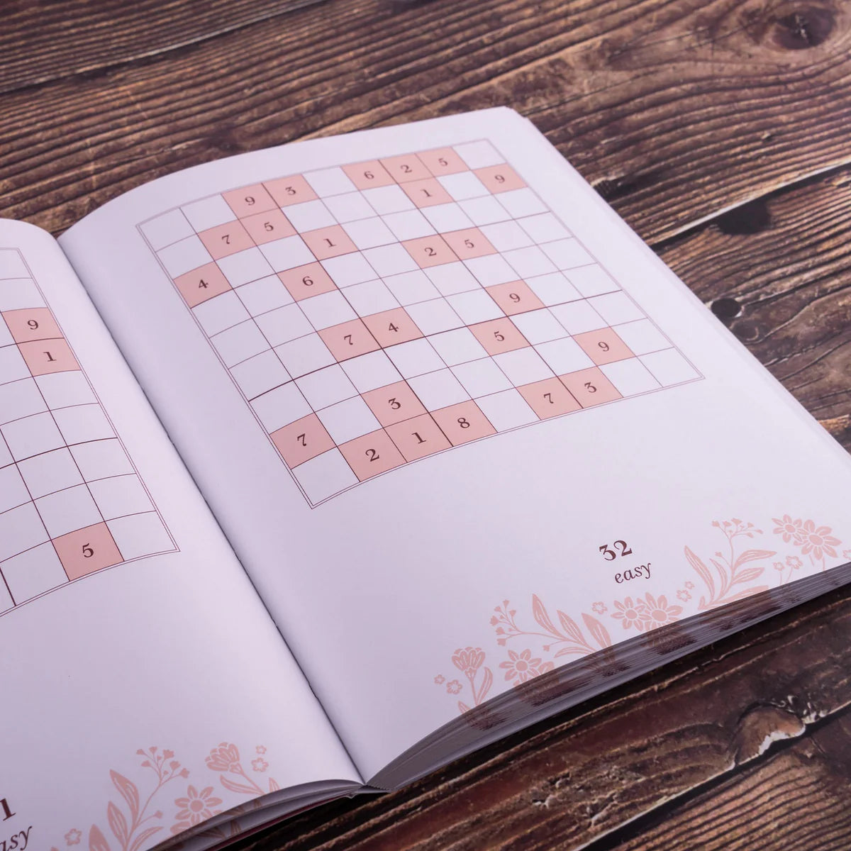Open book with Sudoku puzzles on a wooden surface