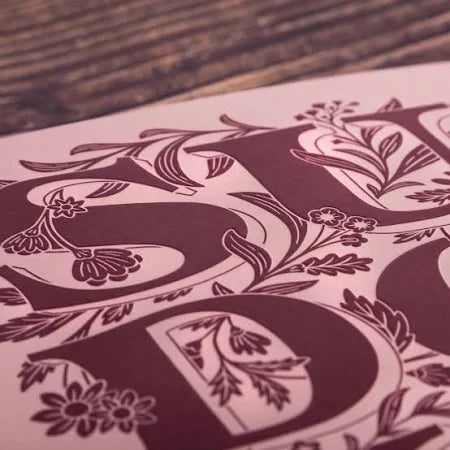 Decorative letter 'S' with floral elements on a wooden surface