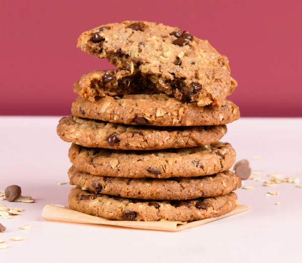 Stack of oatmeal chocolate chip cookies on a white surface with a purple background