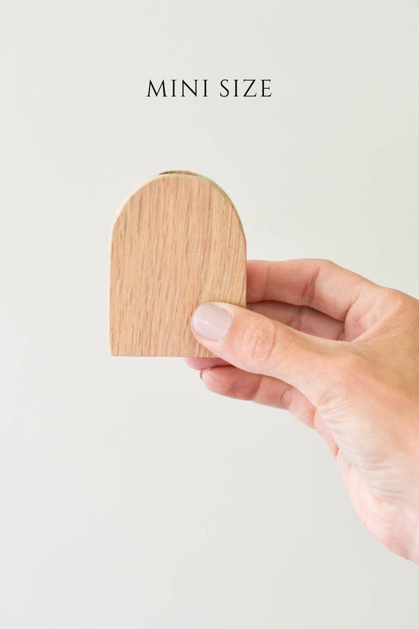 A hand holding a mini size wood arched bud vase made from reclaimed white oak barn wood.