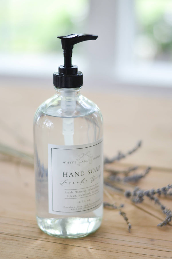 Clear hand soap bottle with black pump on a wooden surface with blurred background