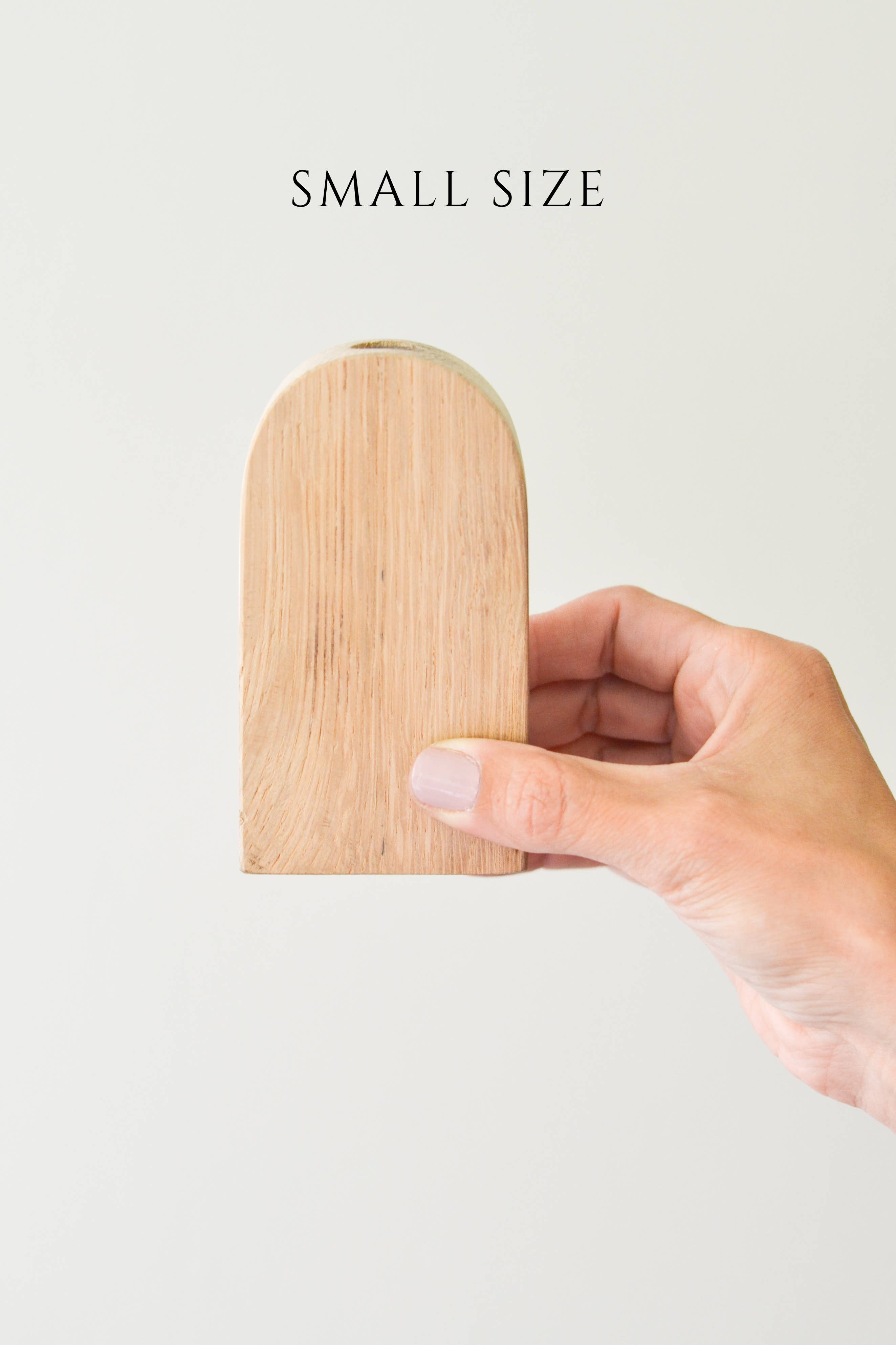 A small size wood arched bud vase held in a person's hand, with a beige color and a visible wood grain texture.