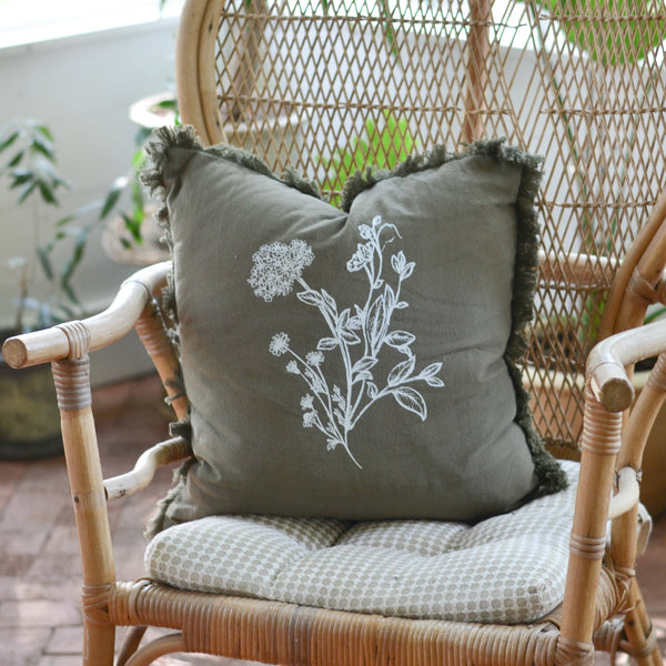 Decorative pillow with floral embroidery on a wicker chair