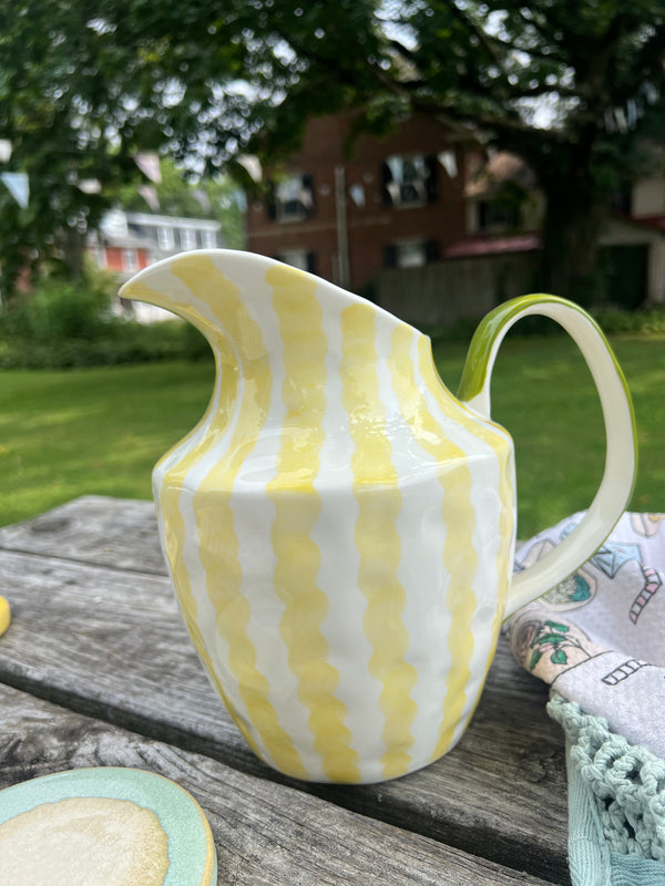 Yellow and white striped pitcher on a wooden surface outdoors