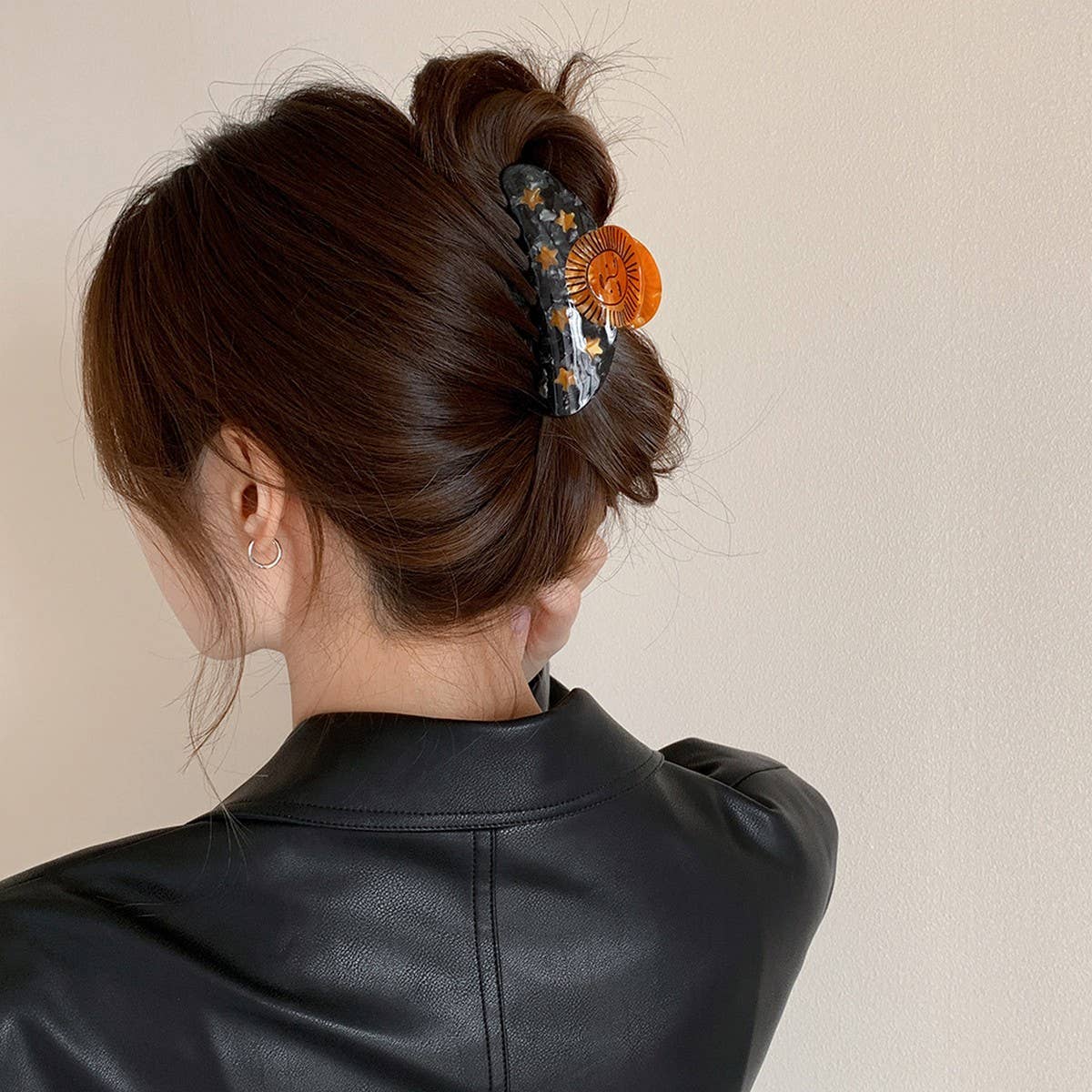 Person with a stylish hair bun decorated with a floral hair accessory against a neutral background