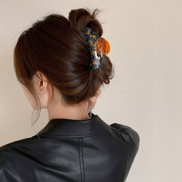 Person with a stylish hair bun decorated with a floral hair accessory against a neutral background
