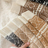 Stack of patterned socks with a hand holding them on a fluffy white surface