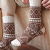 Patterned socks worn by a person sitting on a textured surface.