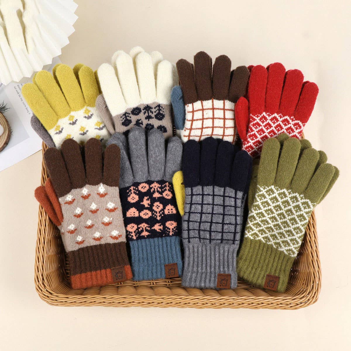 Assorted colorful gloves with patterns arranged in a basket on a light background