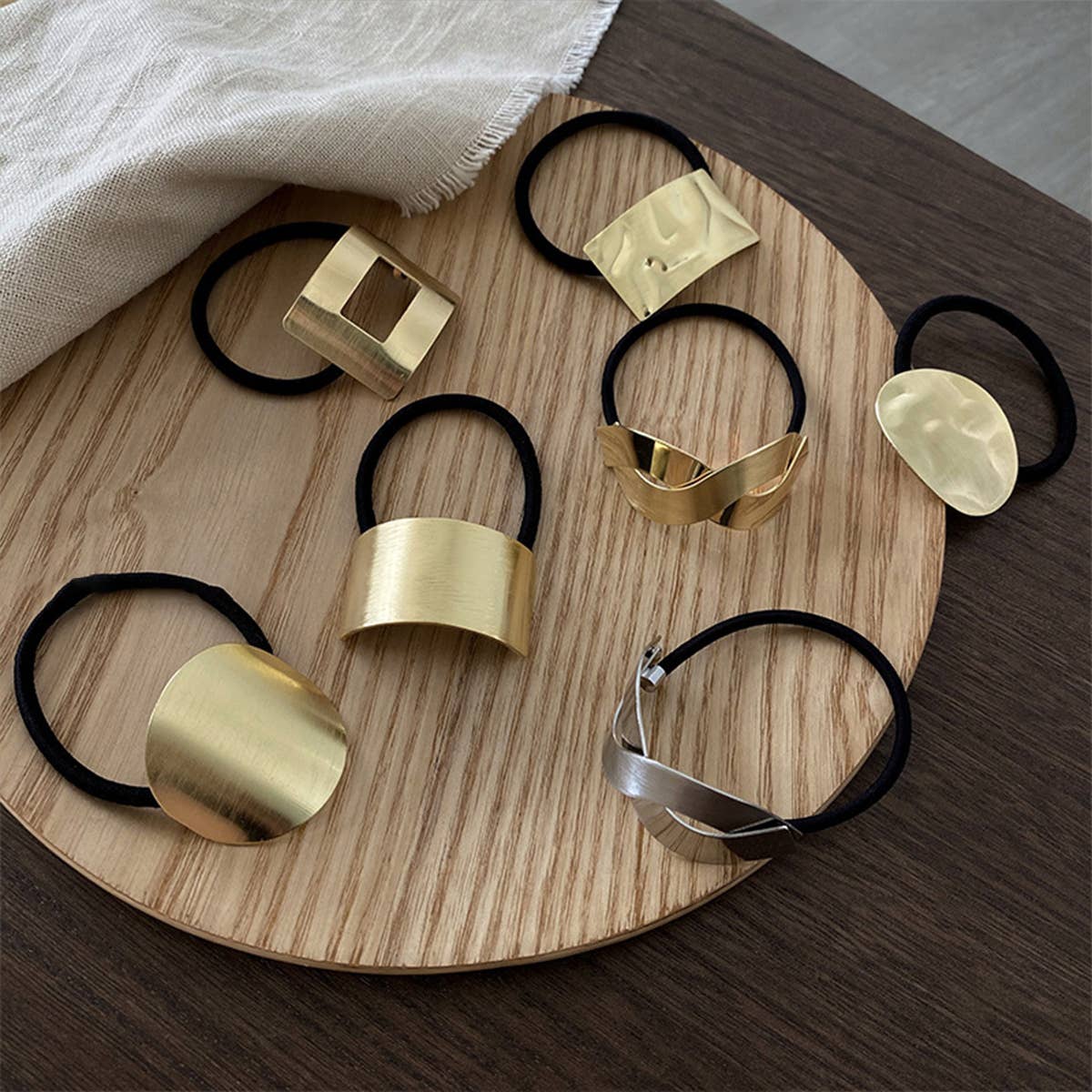 Gold hair ties with various designs on a wooden tray