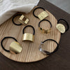 Gold hair ties with various designs on a wooden tray