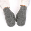 A pair of thick, fuzzy gray knit mittens worn on feet, with the cuffs of light-colored pants visible above the hands against a plain white background.