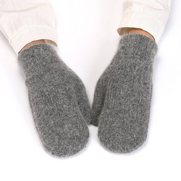 A pair of thick, fuzzy gray knit mittens worn on feet, with the cuffs of light-colored pants visible above the hands against a plain white background.