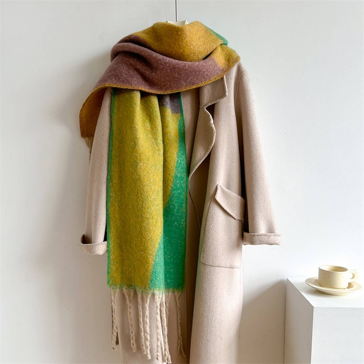 Beige coat with a colorful scarf draped over it on a white background
