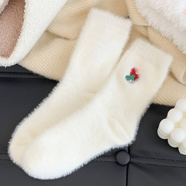 Close-up of a fluffy white glove with a small red and green flower on a black surface.