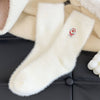 Close-up of a fluffy white boot with a brand logo on a black surface