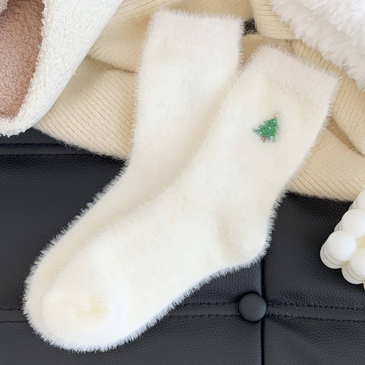 Close-up of a fluffy white dog toy with a green tag on a black surface
