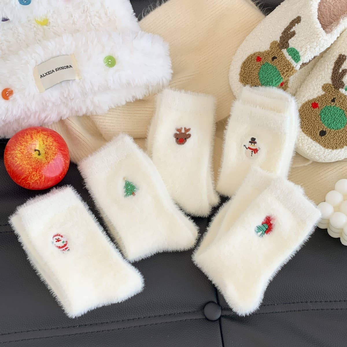 White fluffy phone cases with embroidered designs on a dark surface.