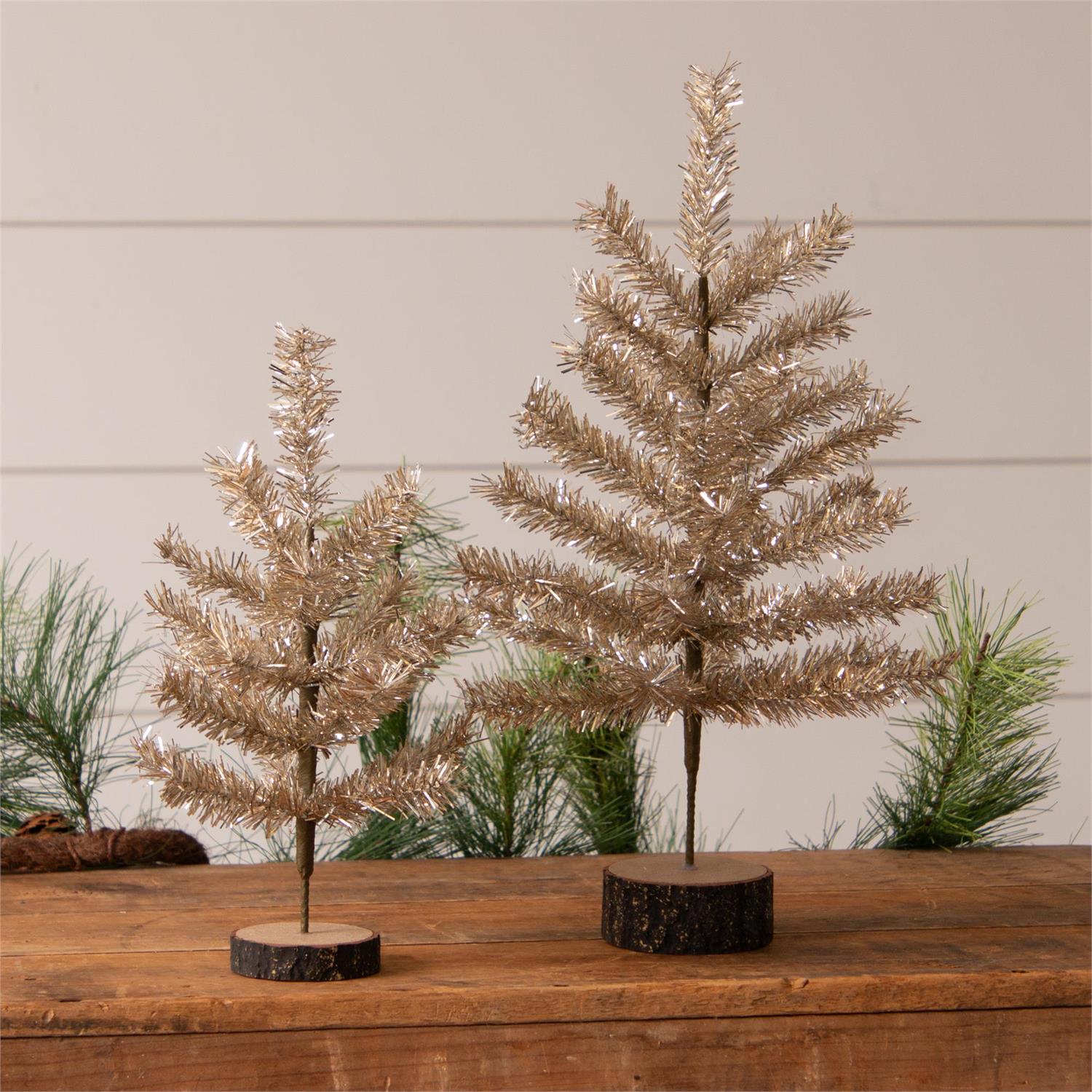 Two gold metallic trees on wooden stands with a neutral background