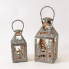 Two metal lanterns with a distressed antique finish, featuring cutout forest and deer patterns, shown on a plain white background.