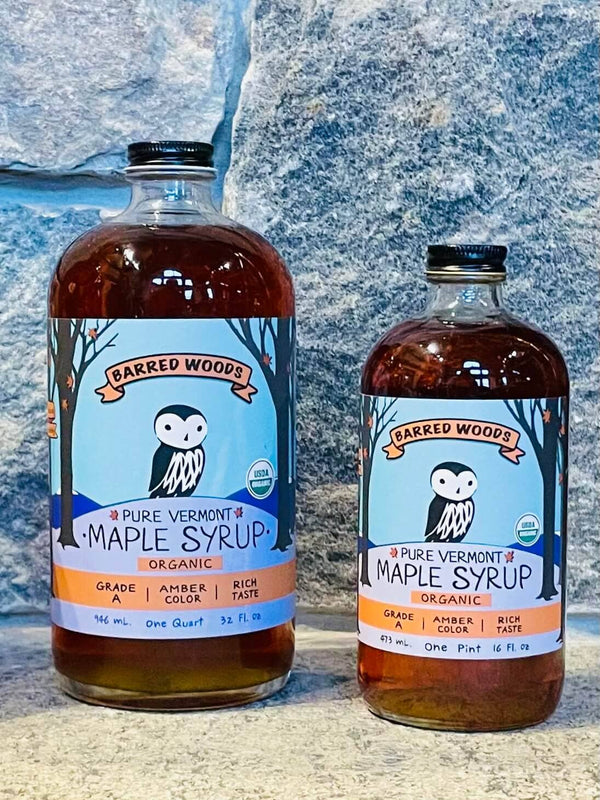 Two bottles of Barred Woods Maple Syrup against a textured blue background