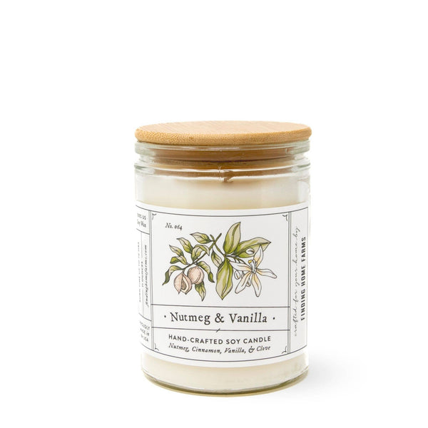 A white candle in a clear glass jar with a wooden lid, labeled 'Nutmeg & Vanilla', depicting illustrations of nutmeg and vanilla plants.