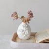 White decorative vase with floral patterns on a tray with an open book
