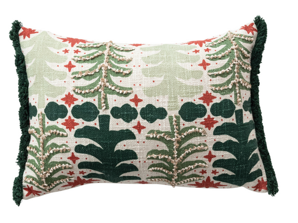 A rectangular decorative throw pillow with a festive embroidered pattern of pine trees, stars, and clouds in green and red on a cream linen background, finished with dark green fringe on the sides.
