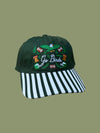 Green cap with embroidered design and striped visor on a green background