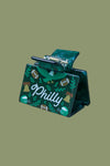 A green hair claw clip with a Philadelphia theme, featuring a hand-drawn eagle, footballs, bells, and the text 'Philly' in white script, resting on a wooden slatted surface.