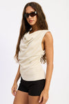 Woman wearing a beige sleeveless top and black shorts on a white background