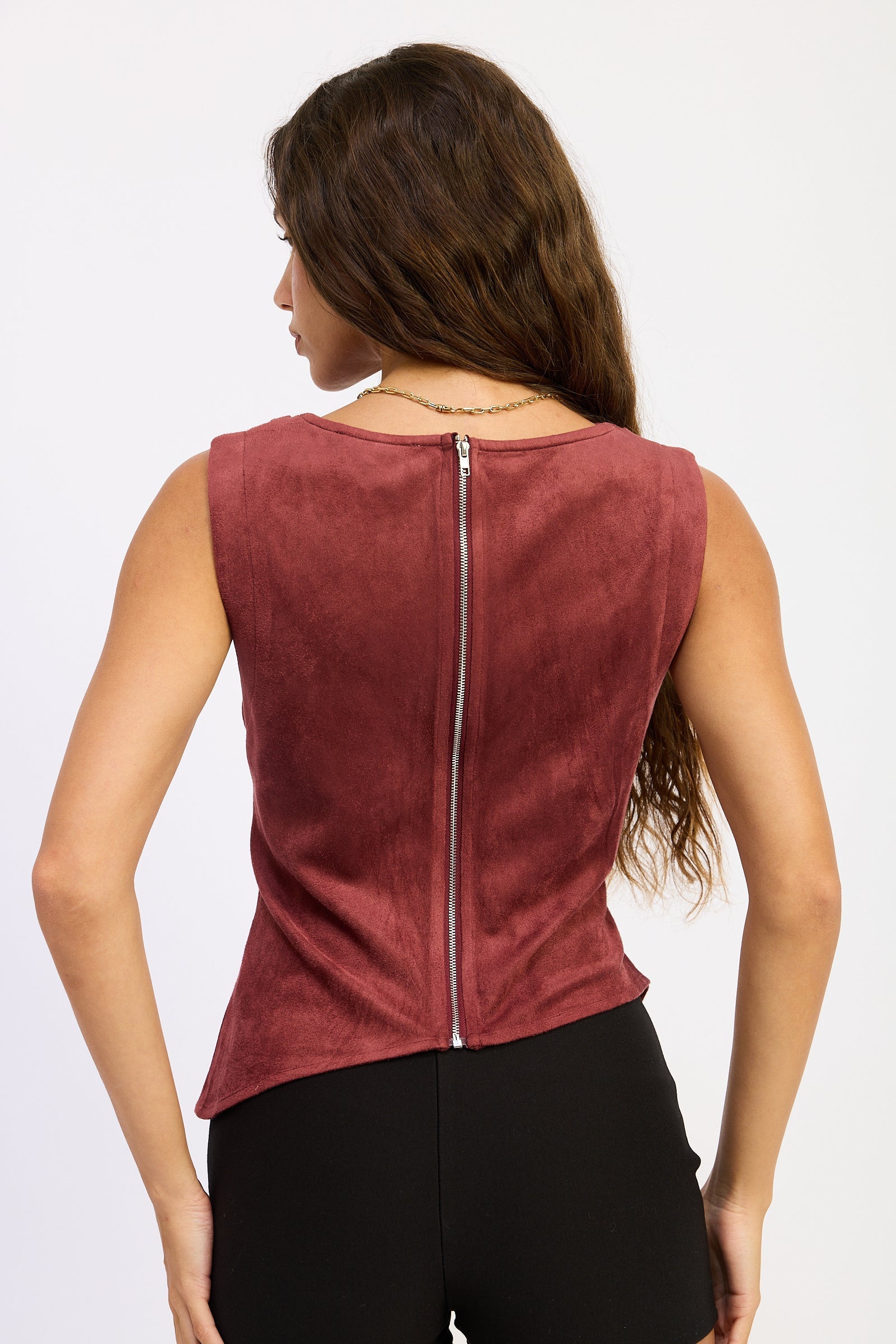 Woman wearing a maroon sleeveless top with a zipper on a white background