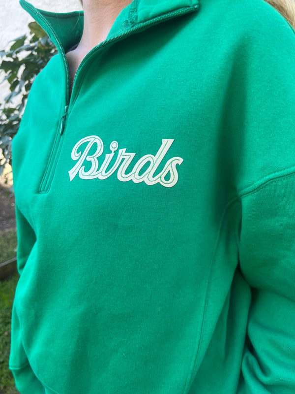 Zoom detail on a green hoodie showing the birds detail in cream lettering and subtle embroidery