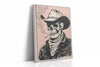 A framed vertical canvas print featuring a black and white sketch of a cowboy skeleton wearing a hat and bandana, smoking a cigarette against a dusty pink background. The canvas is shown standing at an angle on a white reflective surface.