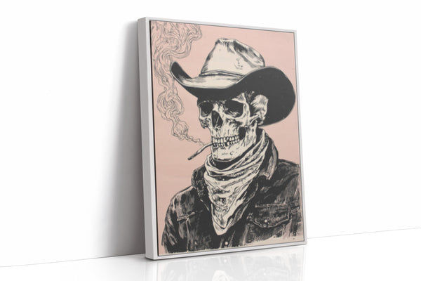 A framed vertical canvas print featuring a black and white sketch of a cowboy skeleton wearing a hat and bandana, smoking a cigarette against a dusty pink background. The canvas is shown standing at an angle on a white reflective surface.